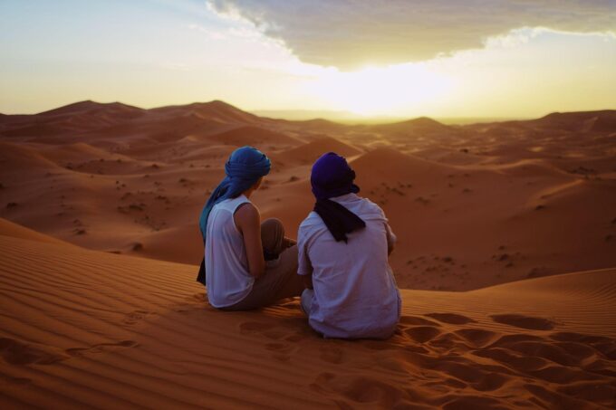 サハラ砂漠で夕日を眺める旅行者