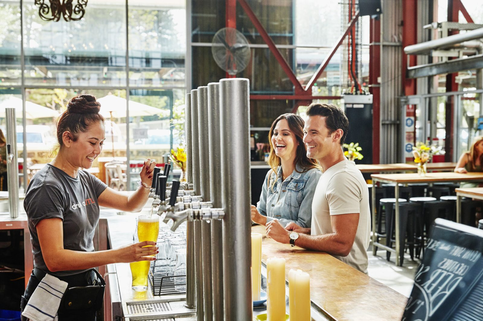 ビールサーバーからビールを注ぐ女性スタッフとビールを待つ客