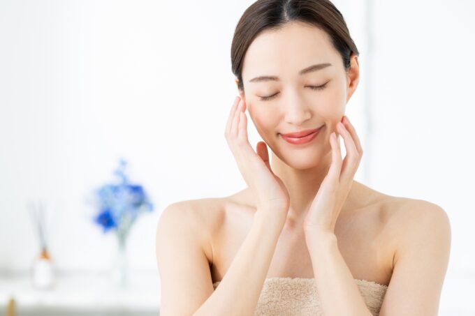 目を閉じて両手をそっと頬に添える美肌の女性
