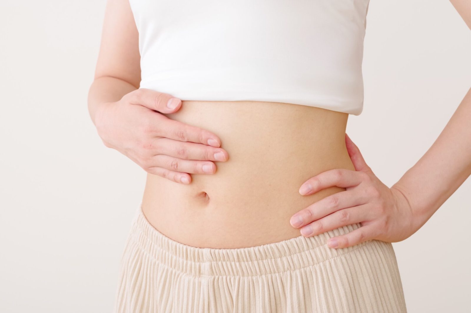 お腹が空いたセパレートな服装でお腹に手を当てる女性