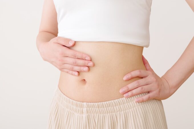 お腹が空いたセパレートな服装でお腹に手を当てる女性