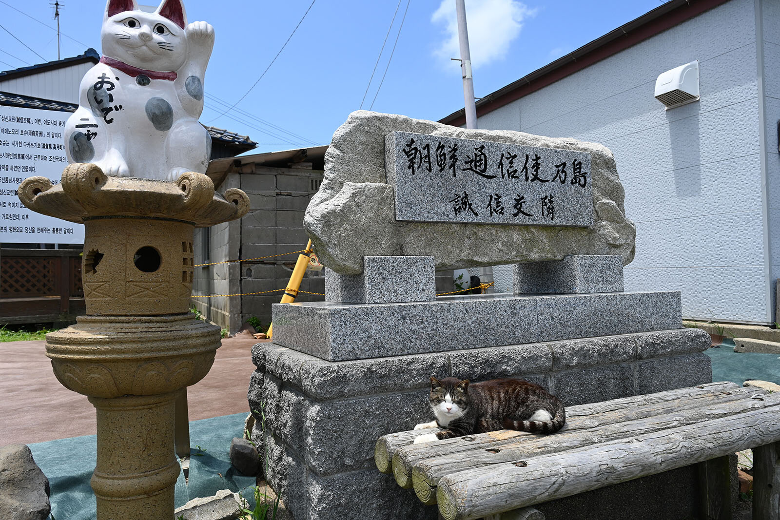 白い招き猫の像に横並びしている朝鮮通信使の島と書かれたモニュメント