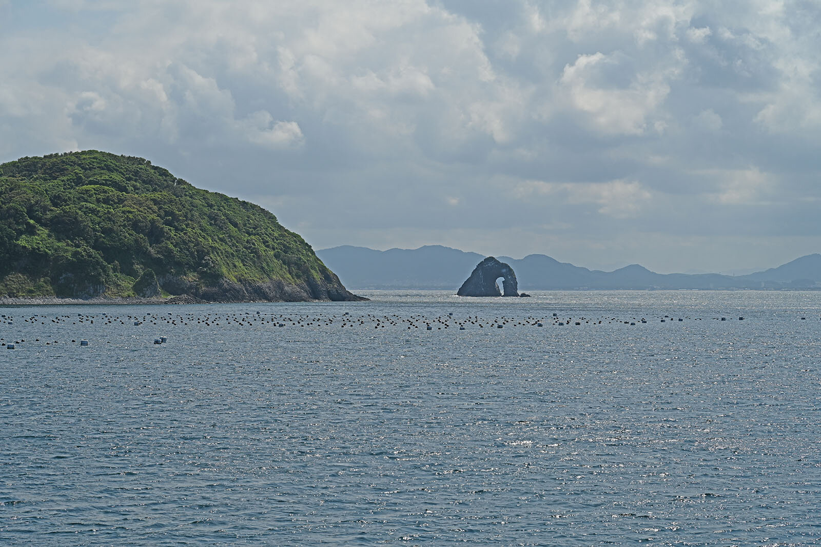 波に削られて大きな穴が空いた珍しい形の岩が、静かに海に佇んでいる景色