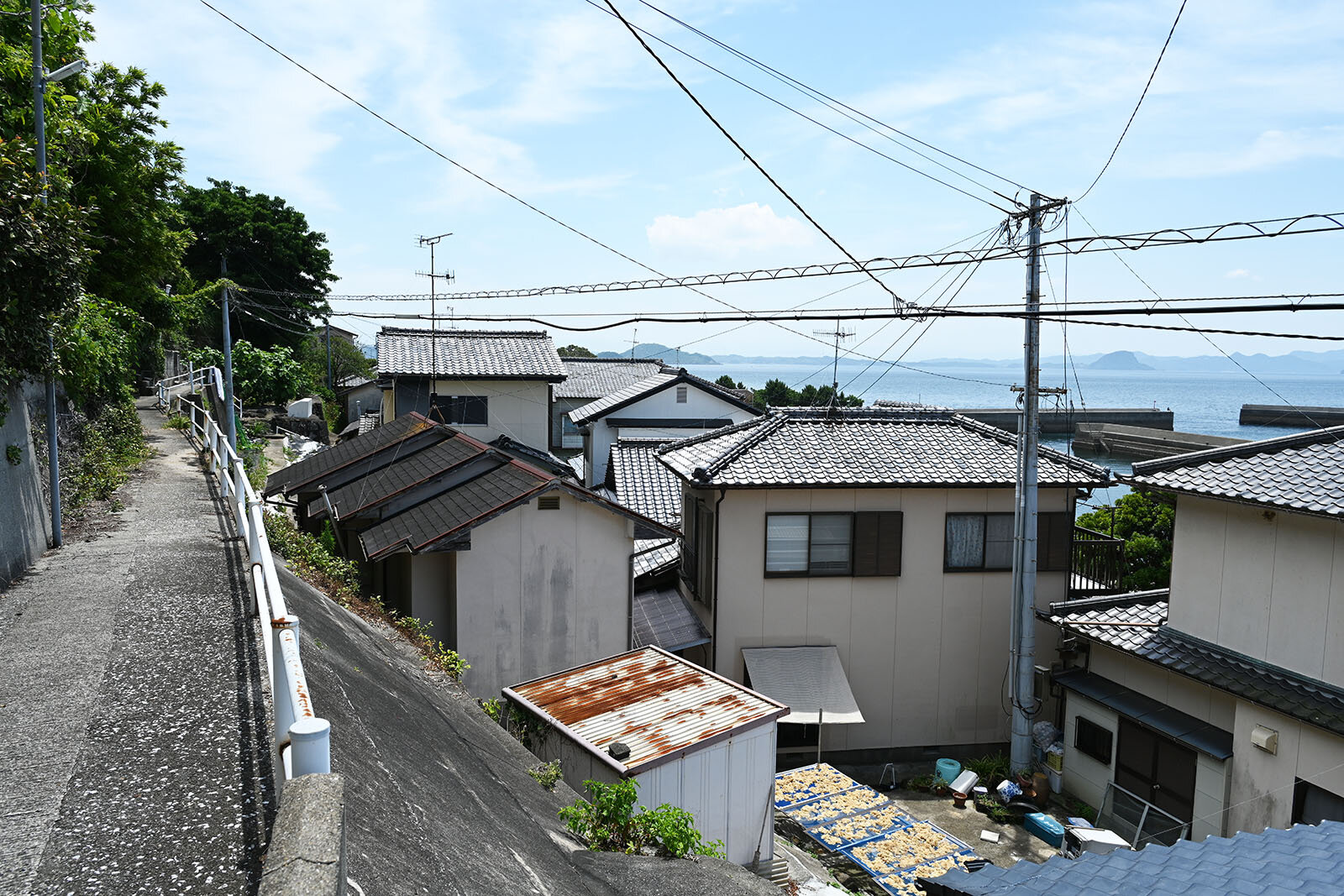 電線が細い道の横に伸び、瓦の家が並んでいる。上から見下ろす景色