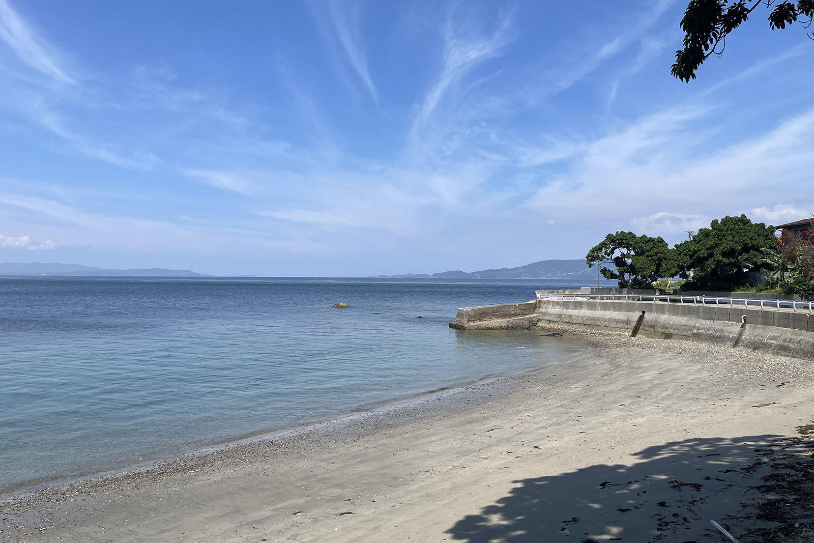 海岸沿いに穏やかな波と静かな砂浜に、澄んだ空が広がっている景色