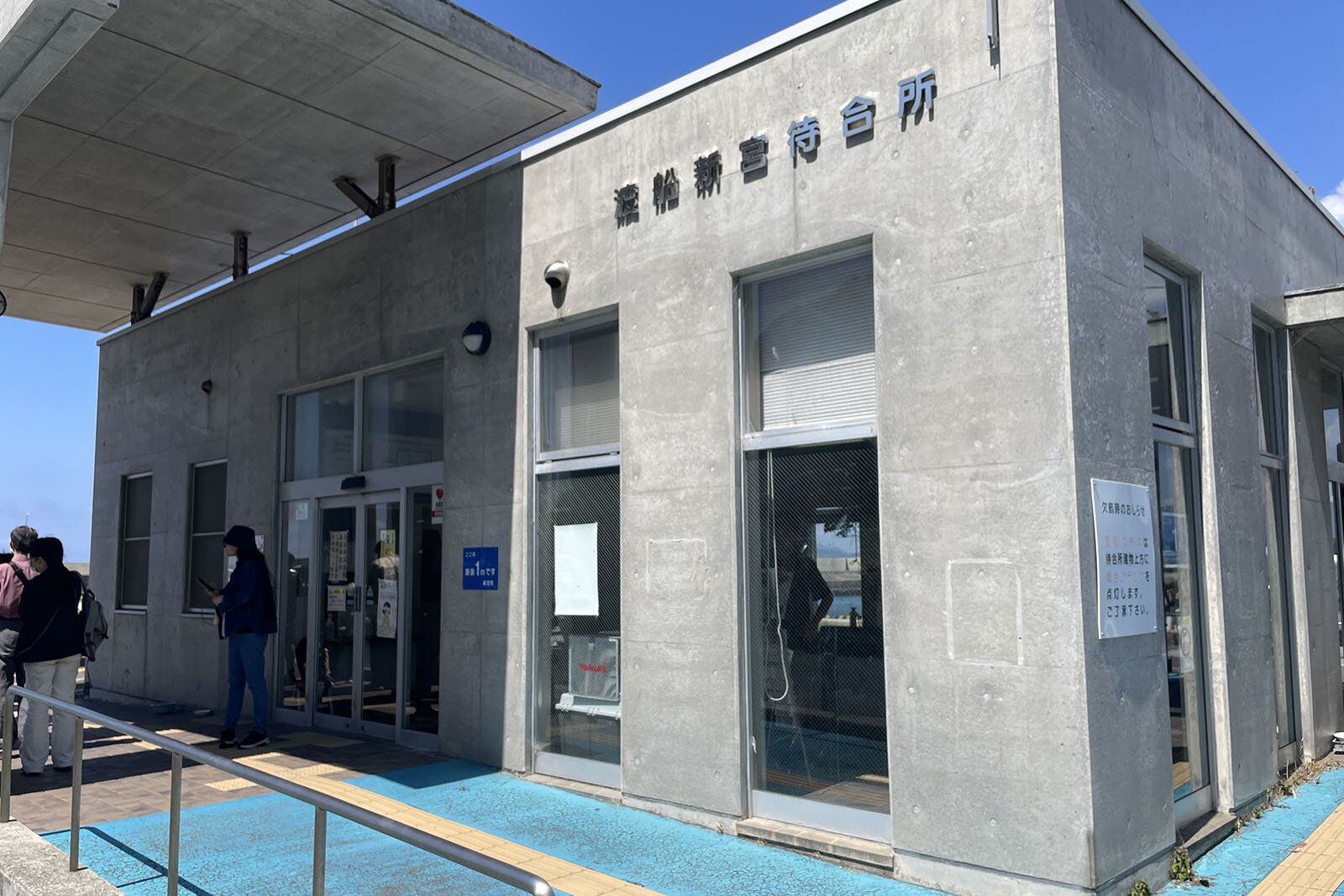 「渡船新宮待合所」と書かれた古い建物と、船の出航を待っている人々