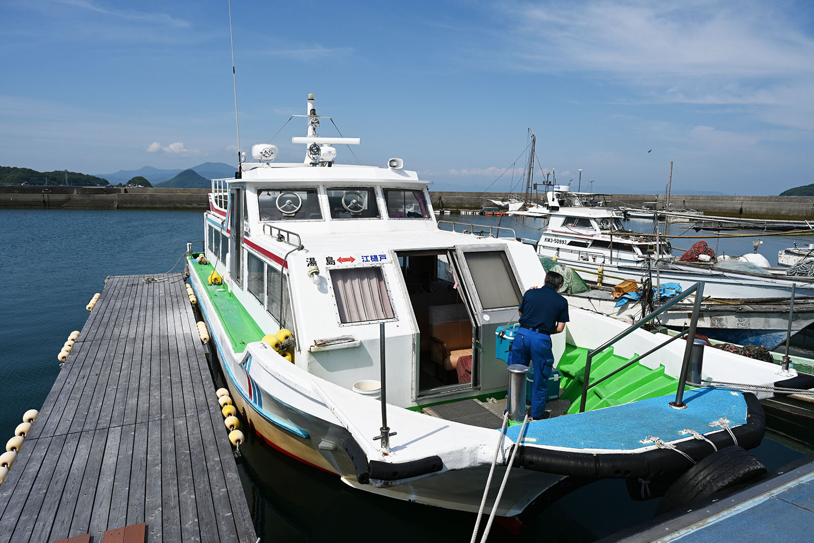 港で湯島の商船が停泊し、作業員が船の整備を行っている景色