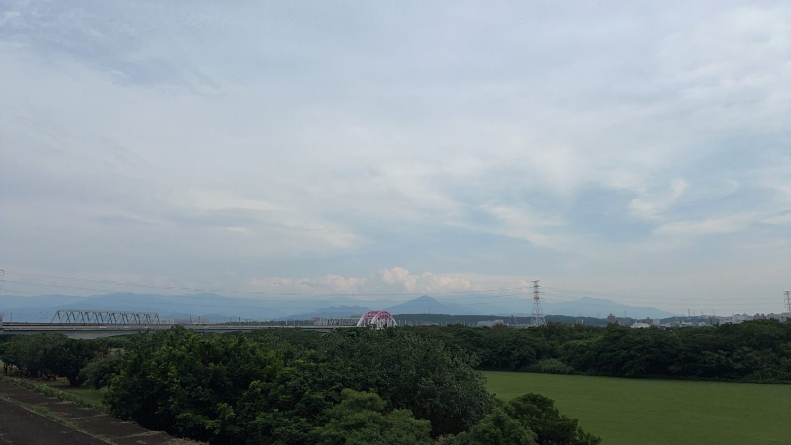 堤防から見える山並み、橋と空の風景