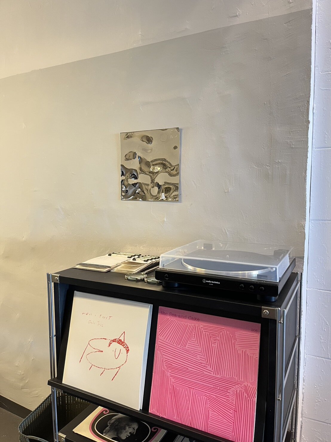 レコードプレーヤーとアート作品が飾られた棚