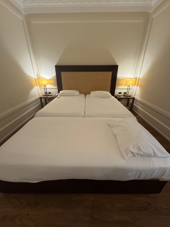 白いベッドが3台置かれたホテルの客室