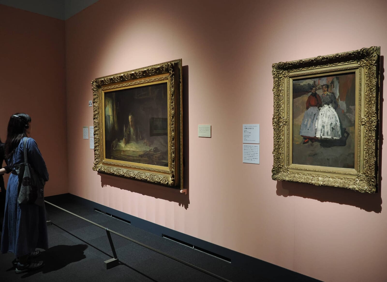 来場者がオーディオガイドを耳に当てながら大型絵画を鑑賞している展示室