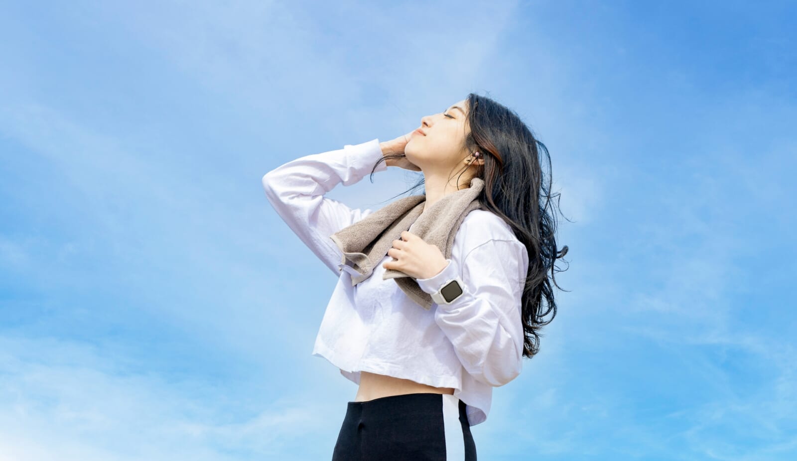 爽やかな青空の下でリフレッシュする女性ランナー