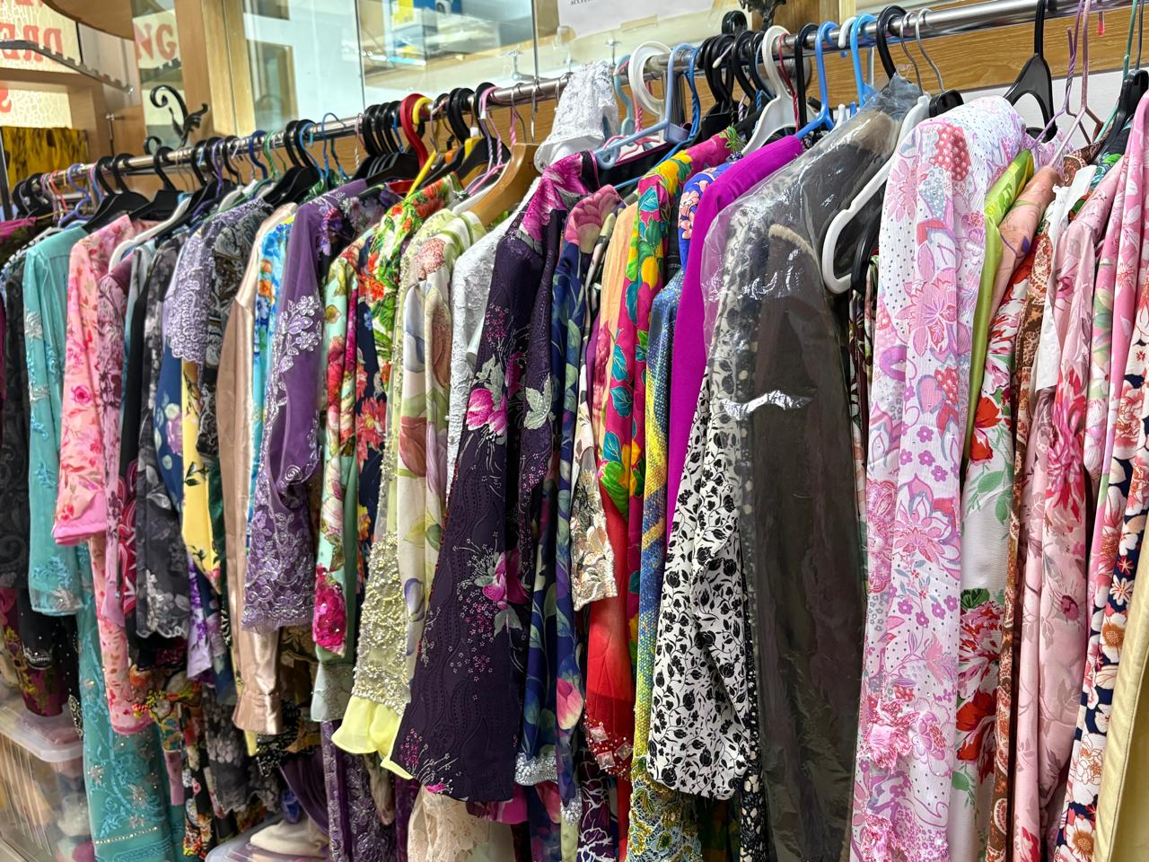 カラフルな花柄ワンピースが並ぶ衣料品店のラック